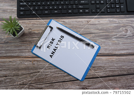 Risk analysis text on blue clipboard with keyboard, pen and potted plant. Flat lay, top view Risk analysis text on blue clipboard with keyboard, pen and potted plant. Flat lay, top view 79715502