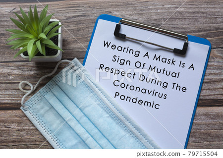 Text on blue clip board with potted plant and face mask on wooden desk Text on blue clip board with potted plant and face mask on wooden desk 79715504