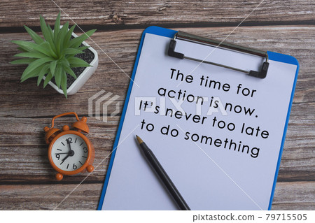 Text on blue clipboard with pen, alarm clock and potted plant on wooden desk 79715505