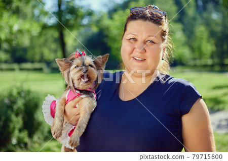 Obese woman with female Yorkshire Terrier in her arms. Obese woman with female Yorkshire Terrier in her arms. 79715800