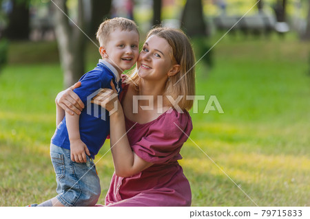 Young woman walks in park with three year old child boy. 79715833