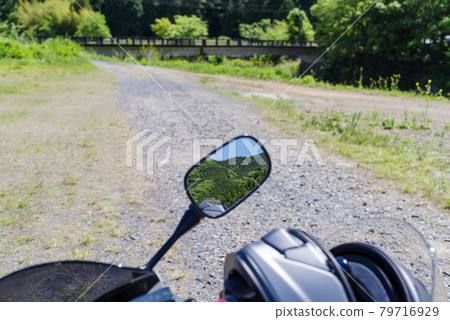 初夏的摩托車旅行在鏡子中反映了未鋪砌的道路和橋樑的模糊背景。 初夏的摩托車旅行在鏡子中反映了未鋪砌的道路和橋樑的模糊背景。 79716929