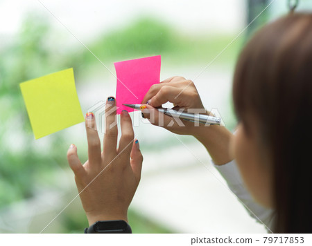 Cropped shot of female writing something on sticky note Cropped shot of female writing something on sticky note 79717853