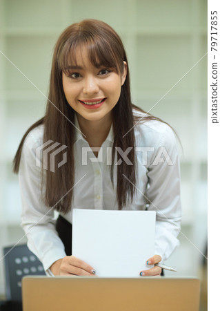 Portrait of attractive female employee smile while preparing financial papers 79717855