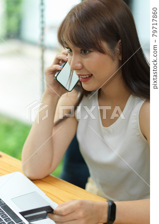 Attractive female making phone call and holding credit card Attractive female making phone call and holding credit card 79717860