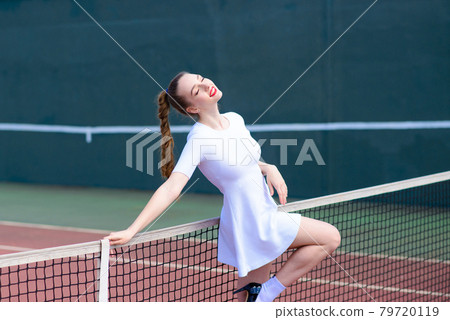 Sensual woman with tennis racket at net on lawn. Activity, energy, power. Sport, training, workout. Wellness, health. Sensual woman with tennis racket at net on lawn. Activity, energy, power. Sport, training, workout. Wellness, health. 79720119