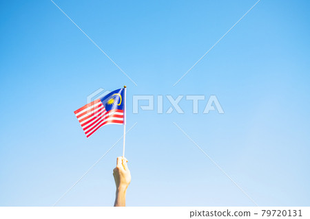 hand holding Malaysia flag on blue sky background. September Malaysia national day and August Independence day hand holding Malaysia flag on blue sky background. September Malaysia national day and August Independence day 79720131