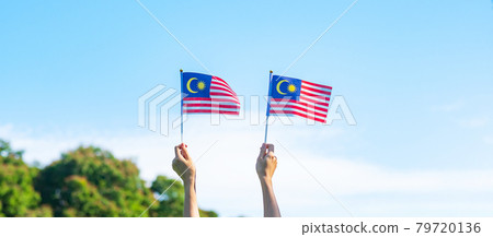 hand holding Malaysia flag on blue sky background. September Malaysia national day and August Independence day hand holding Malaysia flag on blue sky background. September Malaysia national day and August Independence day 79720136