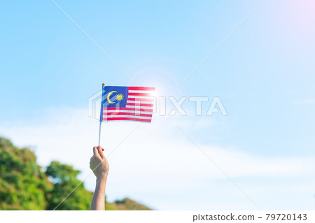 hand holding Malaysia flag on blue sky background. September Malaysia national day and August Independence day hand holding Malaysia flag on blue sky background. September Malaysia national day and August Independence day 79720143