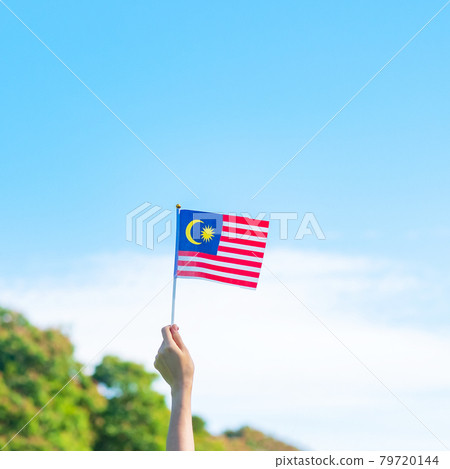 hand holding Malaysia flag on blue sky background. September Malaysia national day and August Independence day hand holding Malaysia flag on blue sky background. September Malaysia national day and August Independence day 79720144