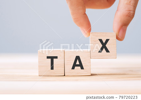 hand holding wood cube block with TAX text . Financial, Management, Economic, business and time to tax concept 79720223