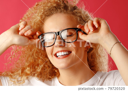 Joyful young curly woman in glasses smiling Joyful young curly woman in glasses smiling 79720320