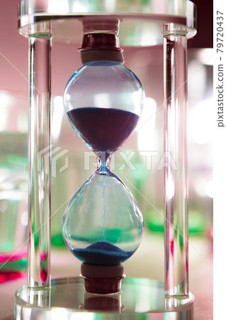 Blue hourglass on gray background close up Blue hourglass on gray background close up 79720437