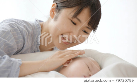 Mother smiling and watching over her sleeping baby, parent and child image 79720799