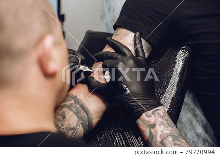 Man doing a tattoo in a tattoo salon 79720994