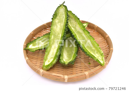 Bitter melon cut in half and with seeds removed served in a colander 79721246