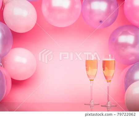 Two glasses of champagne on a pink background with pink and purple balloons. Bright background for celebration. 79722062