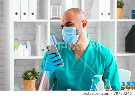 African american doctor or laboratory worker using his smartphone at working place African american doctor or laboratory worker using his smartphone at working place 79723246