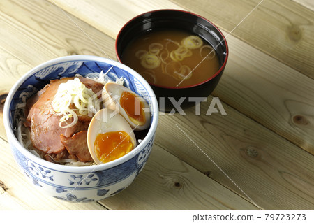 A set of roast pork bowl and miso soup topped with shredded cabbage, taste balls and green onions 79723273