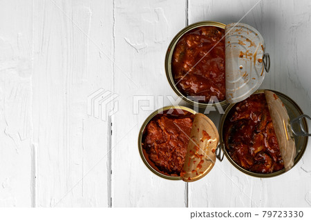 Top view of opened cans with fish conserves on wooden background Top view of opened cans with fish conserves on wooden background 79723330
