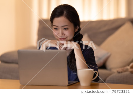 晚上的客廳 一個女人一邊看電腦一邊放鬆 晚上的客廳 一個女人一邊看電腦一邊放鬆 79723331