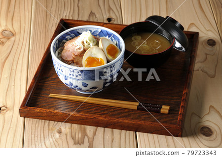 A set of roast pork bowl and miso soup topped with shredded cabbage, taste balls and green onions 79723343
