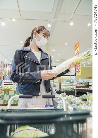 Young female shopper shopping at a supermarket (choosing a radish) 79724748