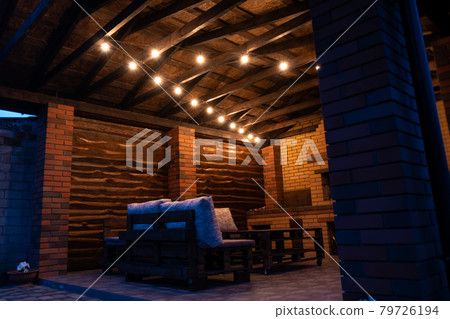 Barbecue area in the evening with antique light bulbs. Furniture made of wood and pallets. Barbecue area in the evening with antique light bulbs. Furniture made of wood and pallets. 79726194
