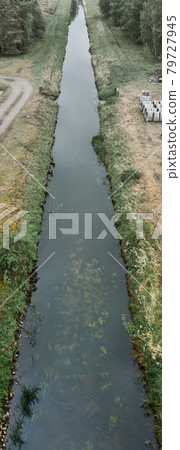 Destruction of nature through a straight drainage ditch with poor ecological quality Destruction of nature through a straight drainage ditch with poor ecological quality 79727945