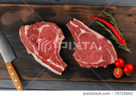 Raw rib eye steak on brown wooden board Raw rib eye steak on brown wooden board 79728662