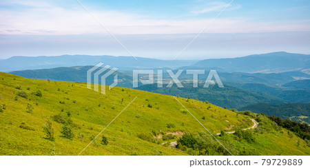 country road through the hill. mountain landscape in morning light. blue sky with clouds on a horizon above the distant ridge. rural valley between the rolling hills in the distance 79729889