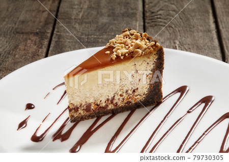 Slice of cheesecake with chocolate, nuts and caramel on shortcrust pastry 79730305
