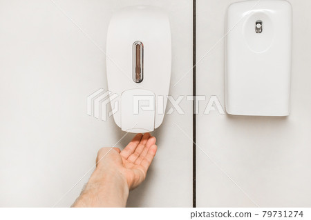 The man raised his hand to the soap dispenser next to the fresh air spray The man raised his hand to the soap dispenser next to the fresh air spray 79731274