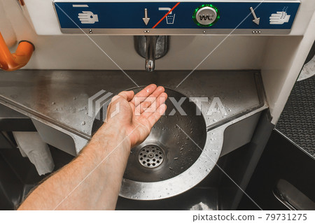 The guy brings his hand to the automatic water supply tap in the modern toilet of the stadler electric train The guy brings his hand to the automatic water supply tap in the modern toilet of the stadler electric train 79731275