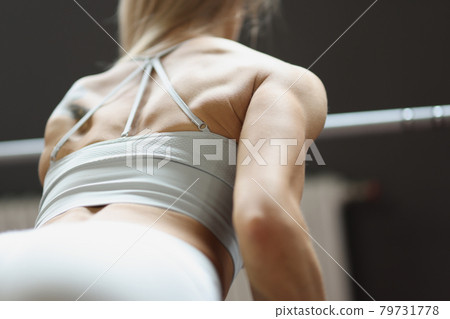 Woman athlete lifting dumbbells in gym back view closeup 79731778
