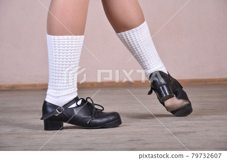 Close-up of female legs in black leather shoes dancing national Irish dances. 79732607