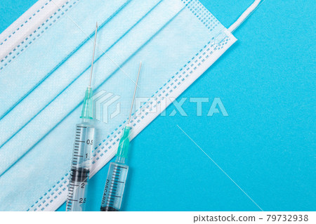 Syringe with Medical Mask on Blue Table - Flat Lay Syringe with Medical Mask on Blue Table - Flat Lay 79732938