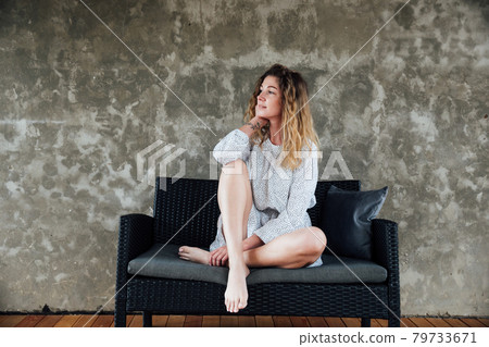 portrait of a beautiful fashionable woman in a light dress on the loft sofa 79733671