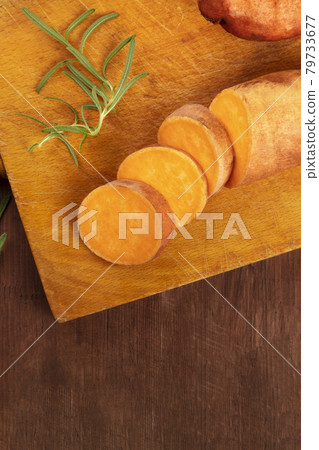 Slices of sweet potatoes with fresh rosemary and copy space Slices of sweet potatoes with fresh rosemary and copy space 79733677