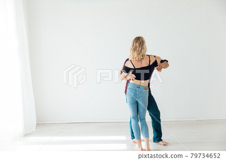 beautiful man and woman dancing together to music in a white room 79734652
