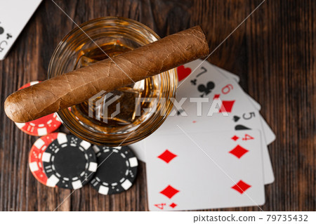 Playing poker with whiskey and cigars on table 79735432
