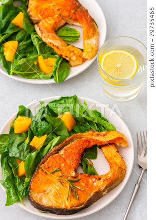 Fried salmon steak with spinach and yellow tomatoes 79735468