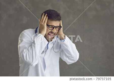 Angry stressed doctor screaming and closing ears with hands isolated on gray background 79737105