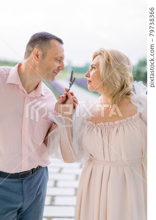 Happy pleasant mature couple in love, standing together outdoors and enjoying the scent of lavender Happy pleasant mature couple in love, standing together outdoors and enjoying the scent of lavender 79738366
