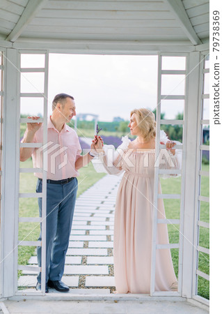 mature elegant couple, standing outside of white wooden gazebo mature elegant couple, standing outside of white wooden gazebo 79738369