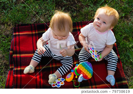 Two twins on a blanket with bright toys look up Two twins on a blanket with bright toys look up 79738619