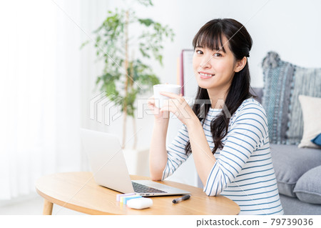 一個少婦遠程辦公在客廳。. 一個少婦遠程辦公在客廳。. 79739036