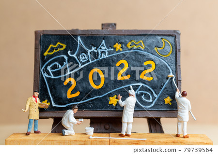 Miniature people worker team painting number 2022 on black board 79739564
