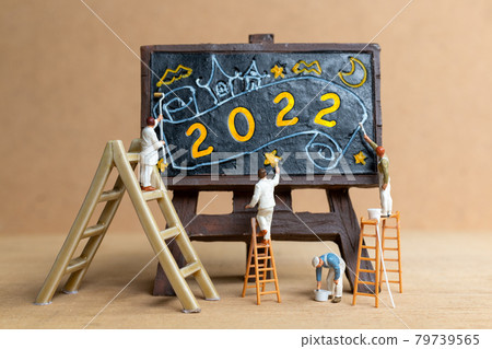 Miniature people worker team painting number 2022 on black board 79739565