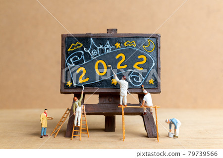 Miniature people worker team painting number 2022 on black board 79739566